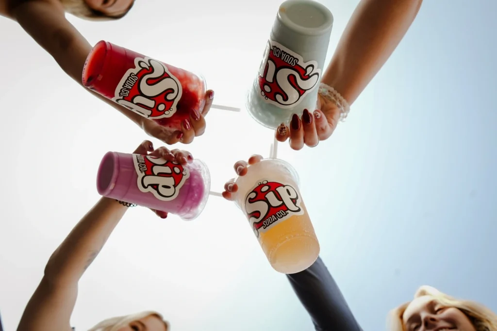 Four friends showing their dirty sodas in Sip Soda cups